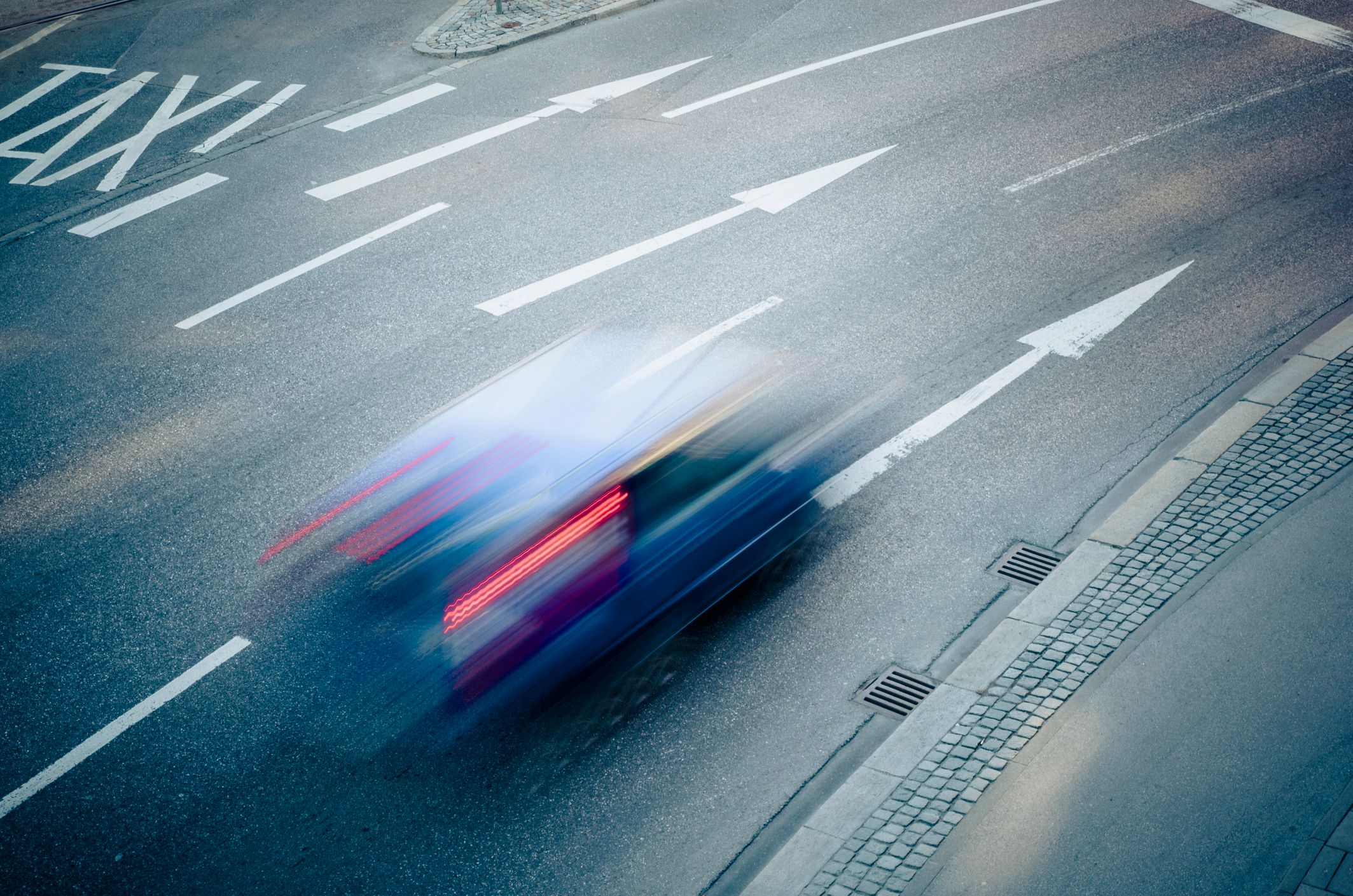 Verschnellertes Bild eines Autos, das mit hoher Geschwindigkeit über eine mehrspurige Straße fährt.
